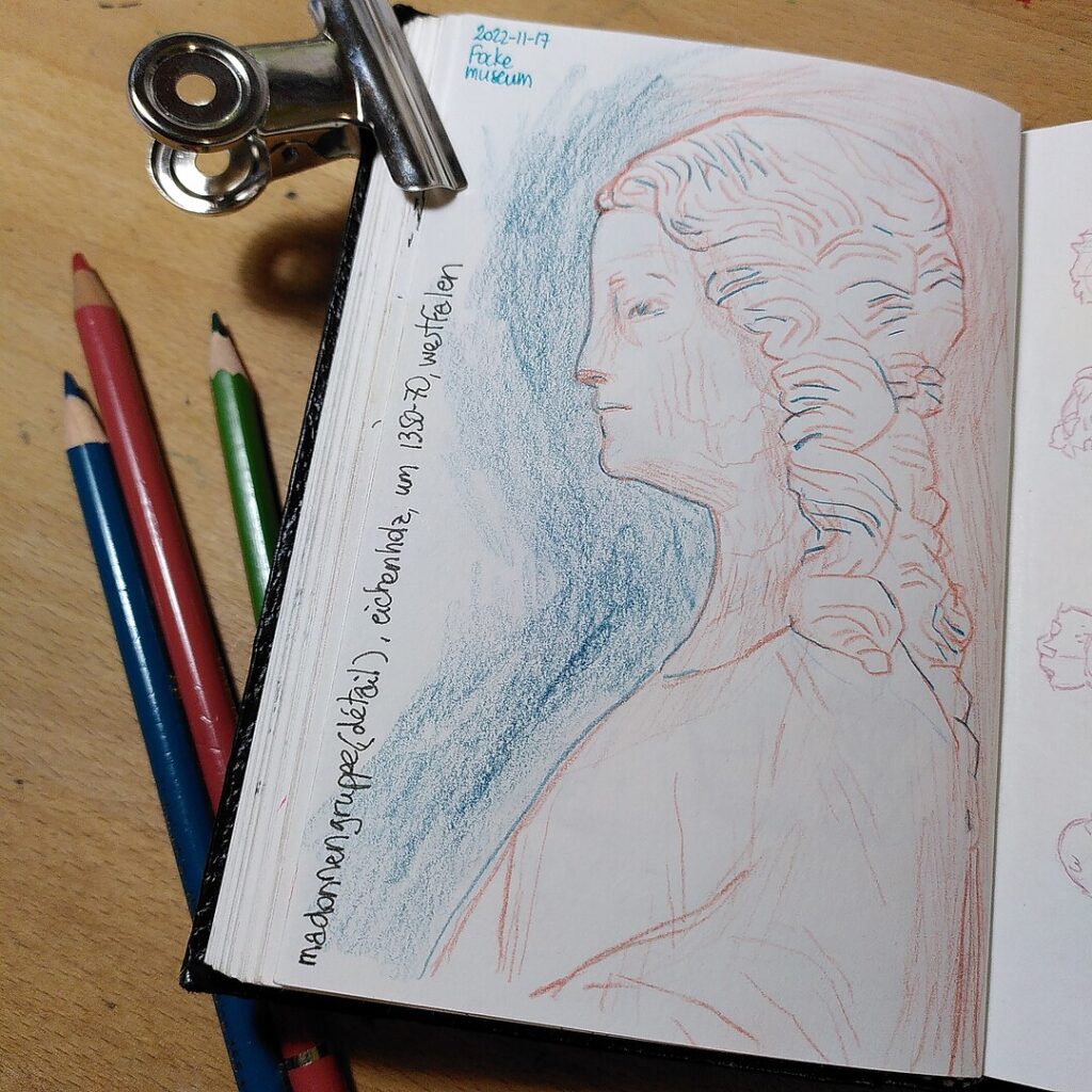 A photo of a sketchbook page with a colour pencil drawing of a woman's bust, and three colour pencils