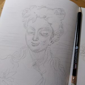 A photo of a sketchbook page with a drawing of a statue (bust) of a woman, also a pencil