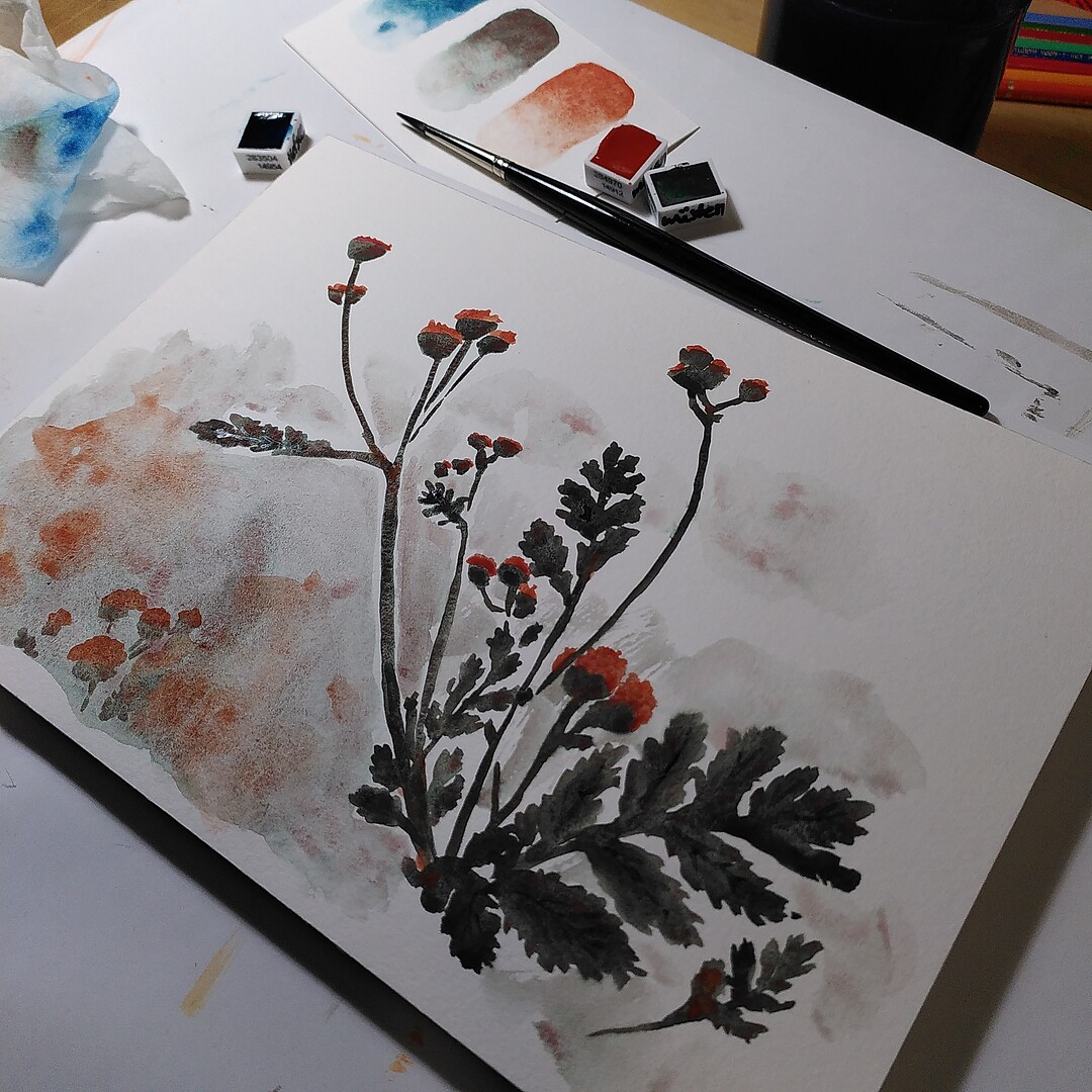 A photo of a watercolour painting of flowers, with painting supplies in the background