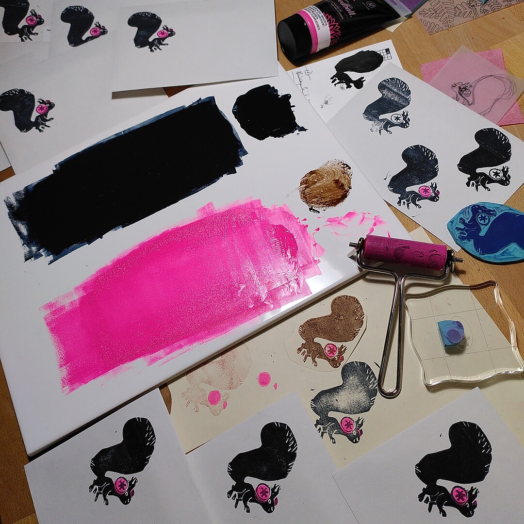 A photo of prints of a squirrel with fluorescent pink earmuffs, and various materials